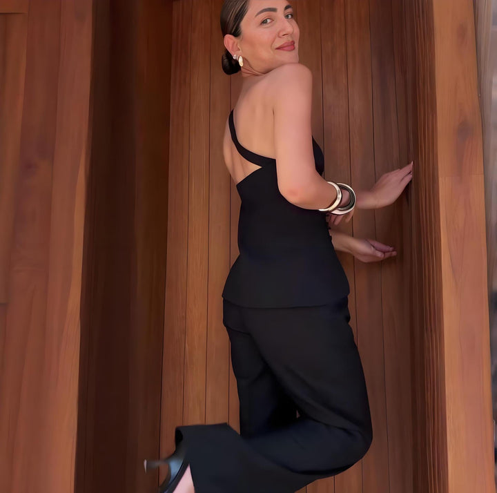 Woman in a black dress standing against a wooden wall