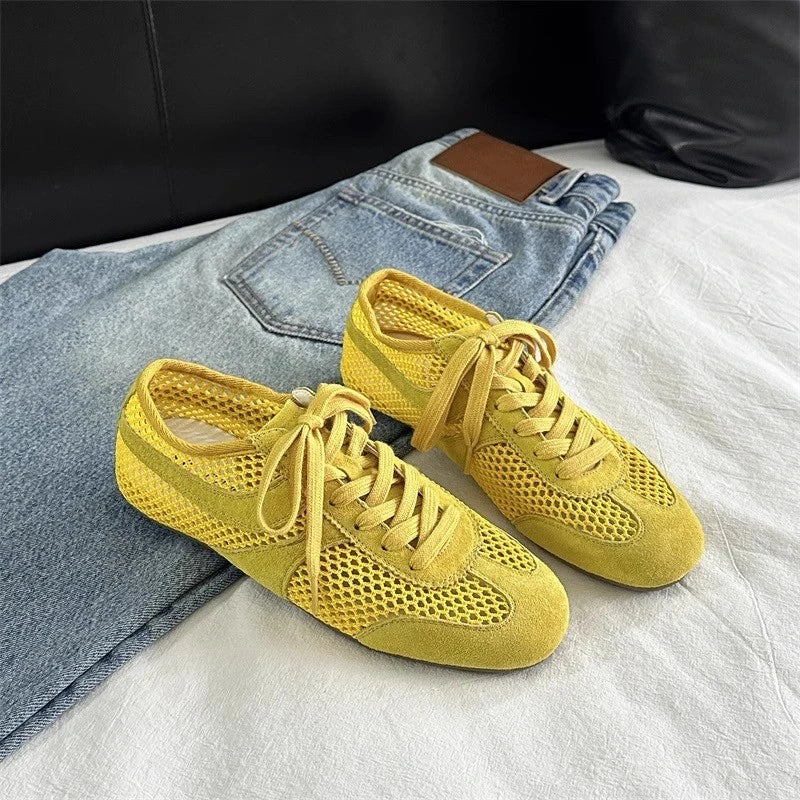 Yellow sneakers on a white surface with jeans in the background