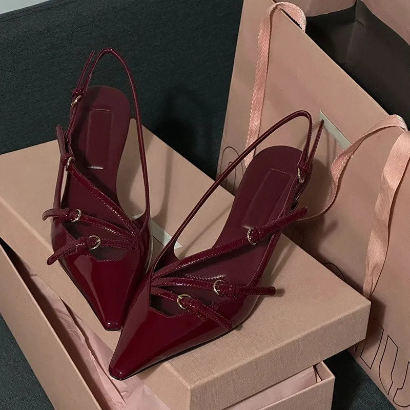 Maroon high-heeled shoes with bow details on a beige box.