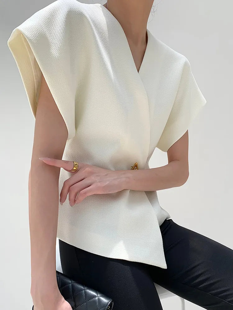 Person wearing a white sleeveless top with a plain background