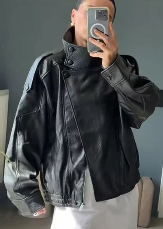 Person wearing a black leather jacket taking a mirror selfie.