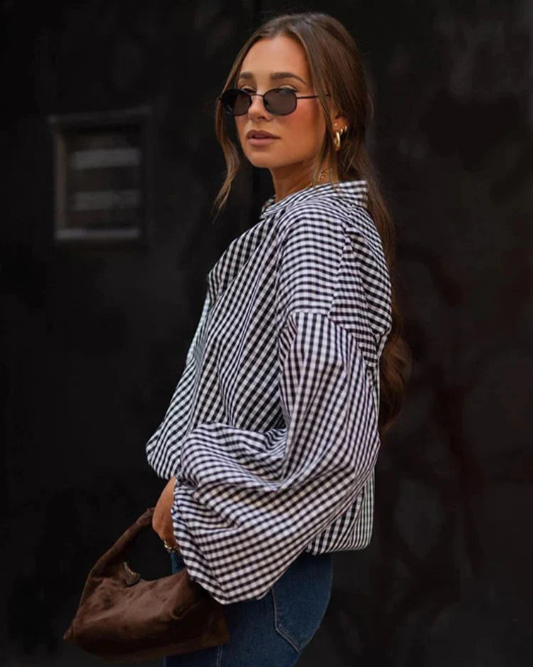 Woman wearing a checkered shirt and sunglasses against a dark background
