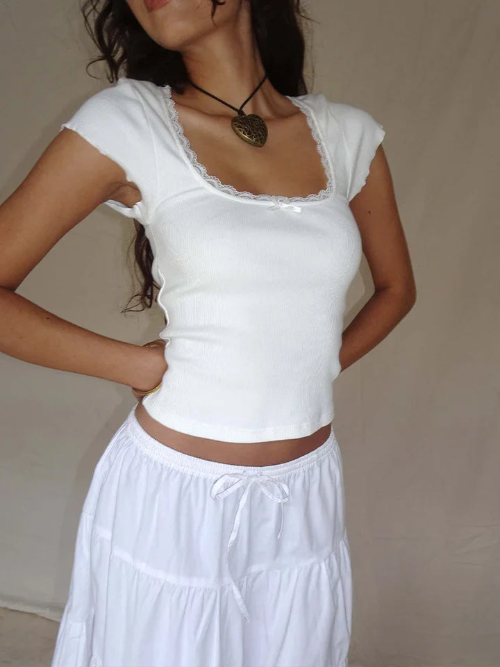 Woman wearing a white top and white skirt against a plain background