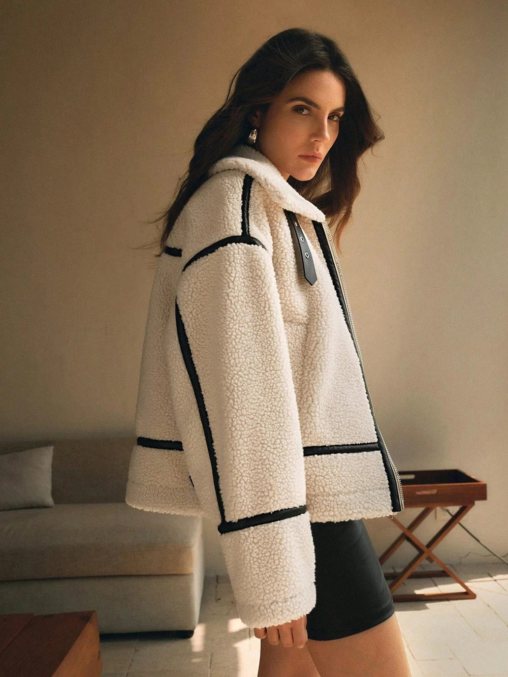 Woman wearing a white coat with black trim in an indoor setting