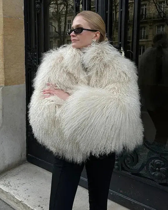 Person wearing a fluffy white coat standing outdoors.