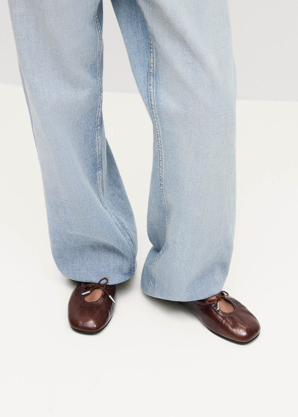 Brown shoes worn with light blue jeans on a white background